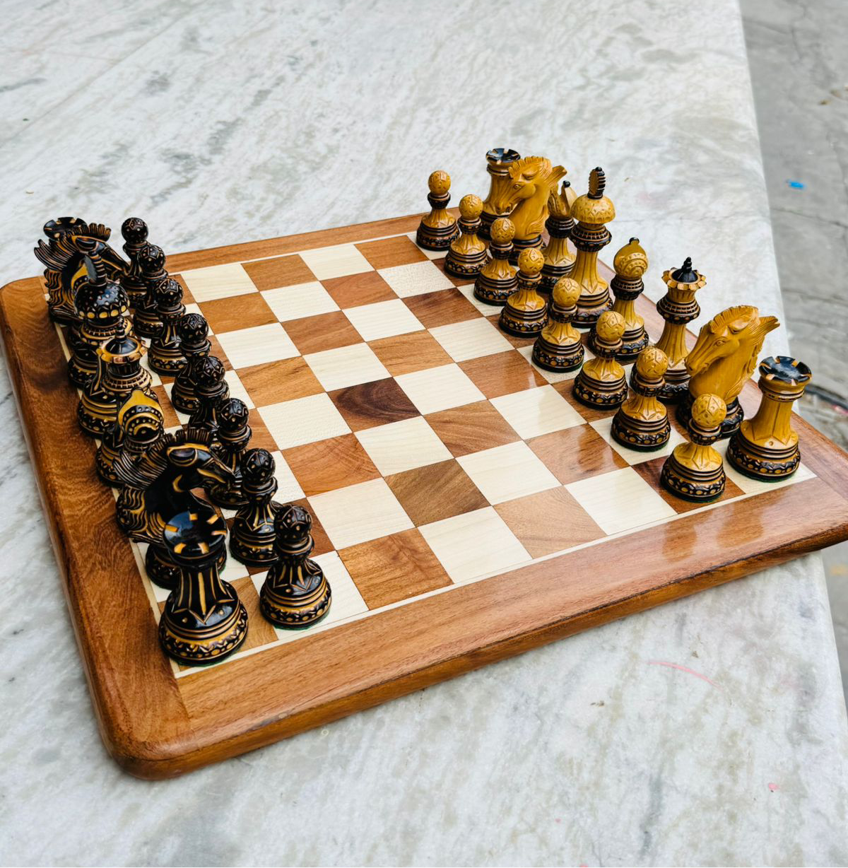 Alexandria Luxury Staunton chess pieces set in boxwood on wooden chess board, featuring hand-carved intricate designs and detailed knights.
