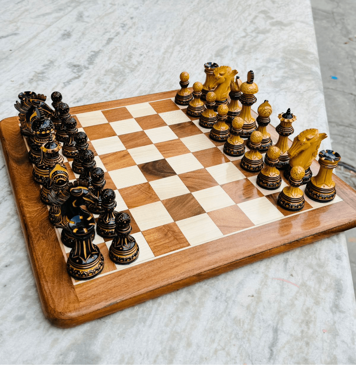 Alexandria Luxury Staunton chess pieces set in boxwood on wooden chess board, featuring hand-carved intricate designs and detailed knights.