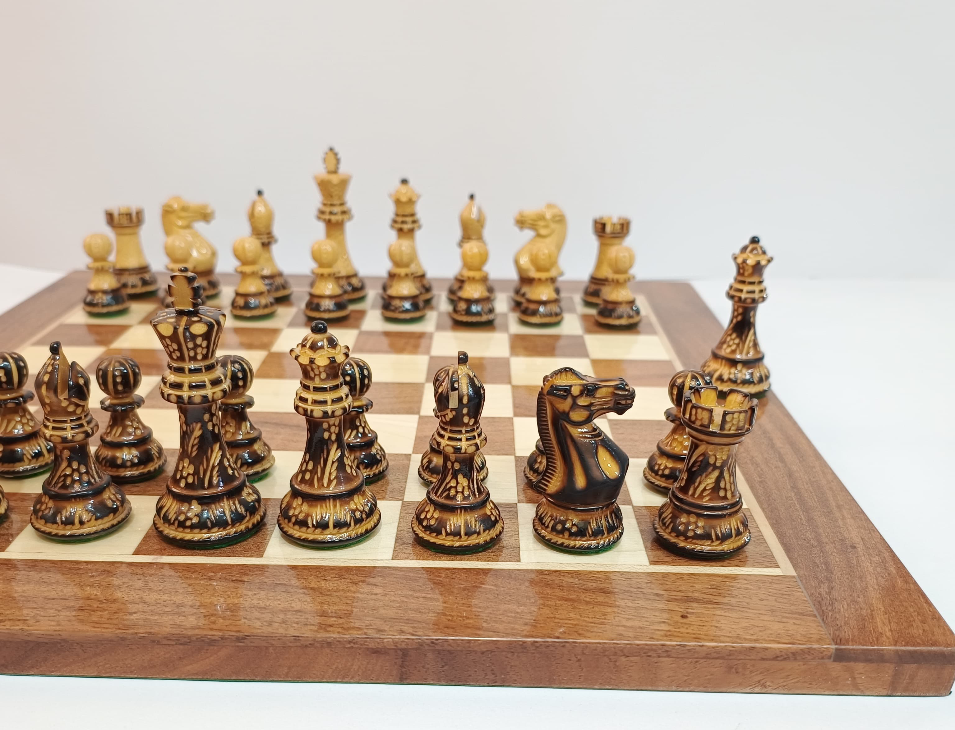 Close-up of a Burnt Staunton wooden chess set with elegant hand-carved pieces on a checkered board.