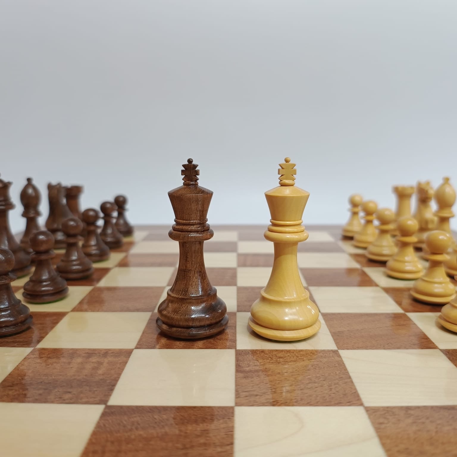 Supreme Fierce Knight Staunton chess pieces on luxury chess board, showcasing wooden king pieces in contrasting colors.