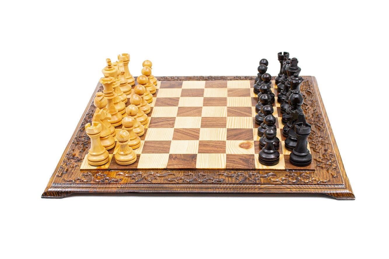Hand carved wooden chess set featuring black and natural colored pieces on a decorative chessboard.