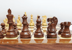 Handcrafted wooden Staunton chess pieces on a luxury chess board in rich dark wood.