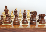 Handcrafted wooden Staunton chess pieces on a luxury chess board in rich dark wood.