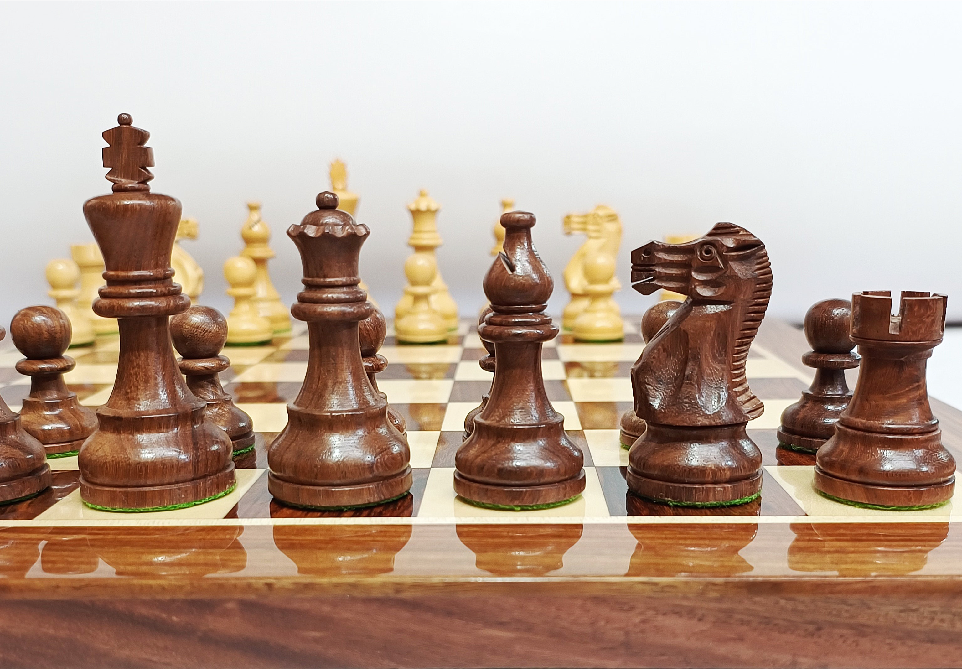 Handcrafted wooden Staunton chess pieces on a luxury chess board in rich dark wood.