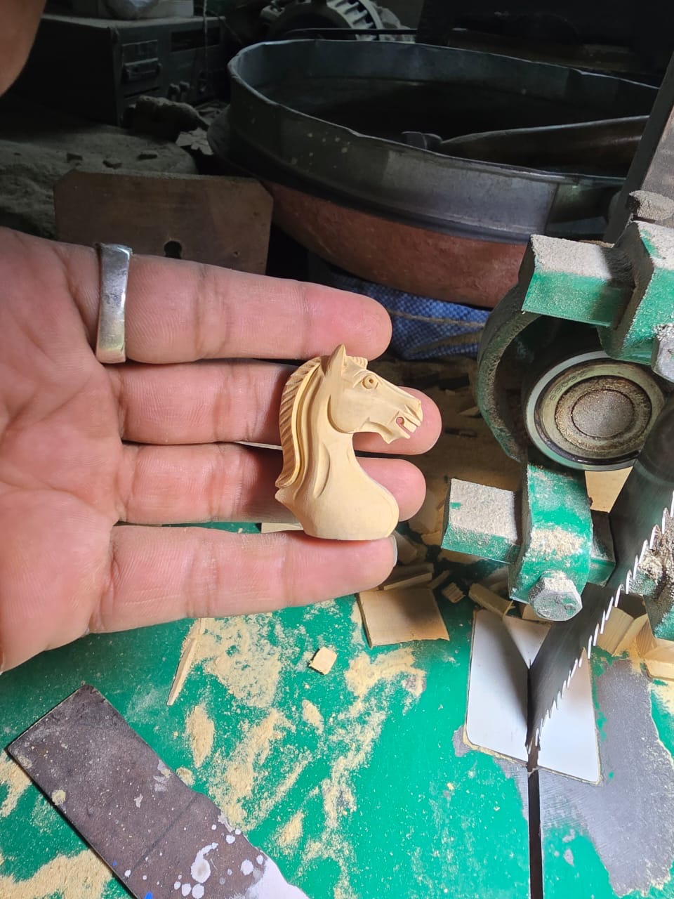 A hand-carved wooden knight held beside tools in the workshop