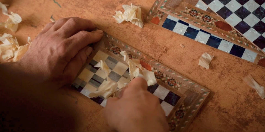 An artisan working by hand on an inlaid chess board