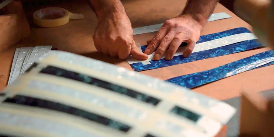 An artisan arranging contrasting decorative strips for a chess board