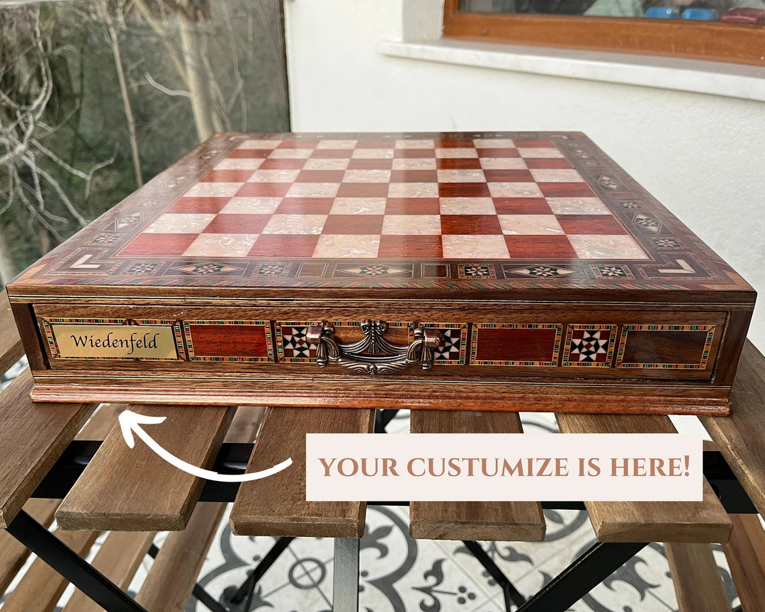 Custom chess set with engraved name 'Wiedenfeld' on a wooden board, displayed on a table.
