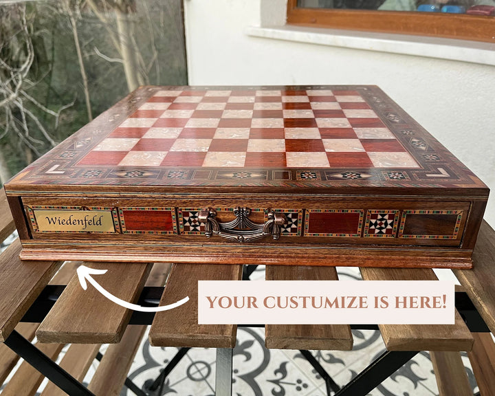 Custom chess set with engraved name 'Wiedenfeld' on a wooden board, displayed on a table.